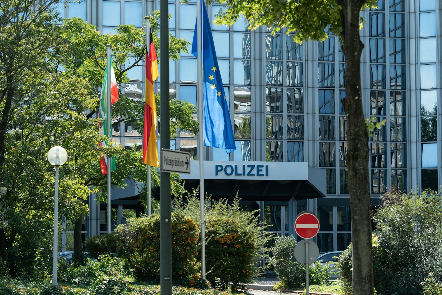 Eingang eines deutschen Polizeireviers mit gehissten Bundes- und Europafahnen.